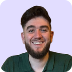 A young man with short dark hair and a beard smiles at the camera. He is wearing a green collared shirt and is set against a light purple background.