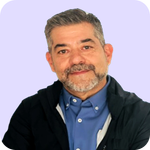 Un hombre de mediana edad, con el pelo corto y canoso y barba, sonríe amablemente. Lleva una camisa azul abotonada y una chaqueta oscura. El fondo es de un color morado claro, que recuerda el ambiente profesional a la par que cercano de un seminario web como «El caso Casual Brands: formación de directivos».