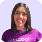 Una mujer sonriente, con el pelo liso y oscuro, que lleva una camiseta morada de Mapal OS, posando frente a un fondo morado claro.