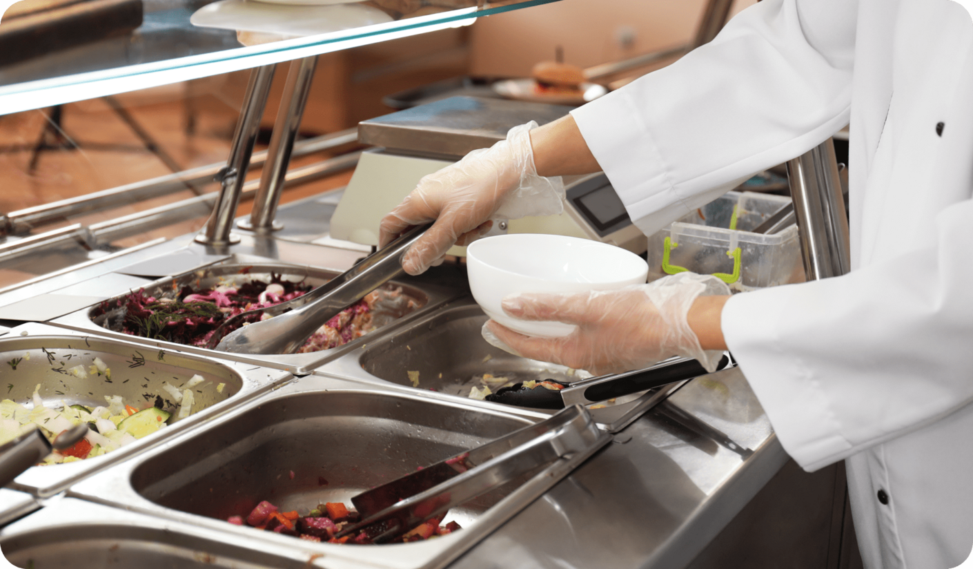 Un chef est en train de préparer des plats dans une cantine scolaire, en utilisant un logiciel de cantine efficace.