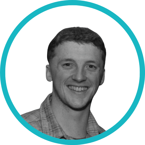 Smiling person with short hair, wearing a checked shirt, shown in black and white inside a thick teal circular frame on a white background.