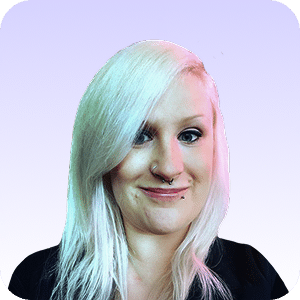 A person with long, platinum blonde hair and facial piercings smiles at the camera against a light purple gradient background.