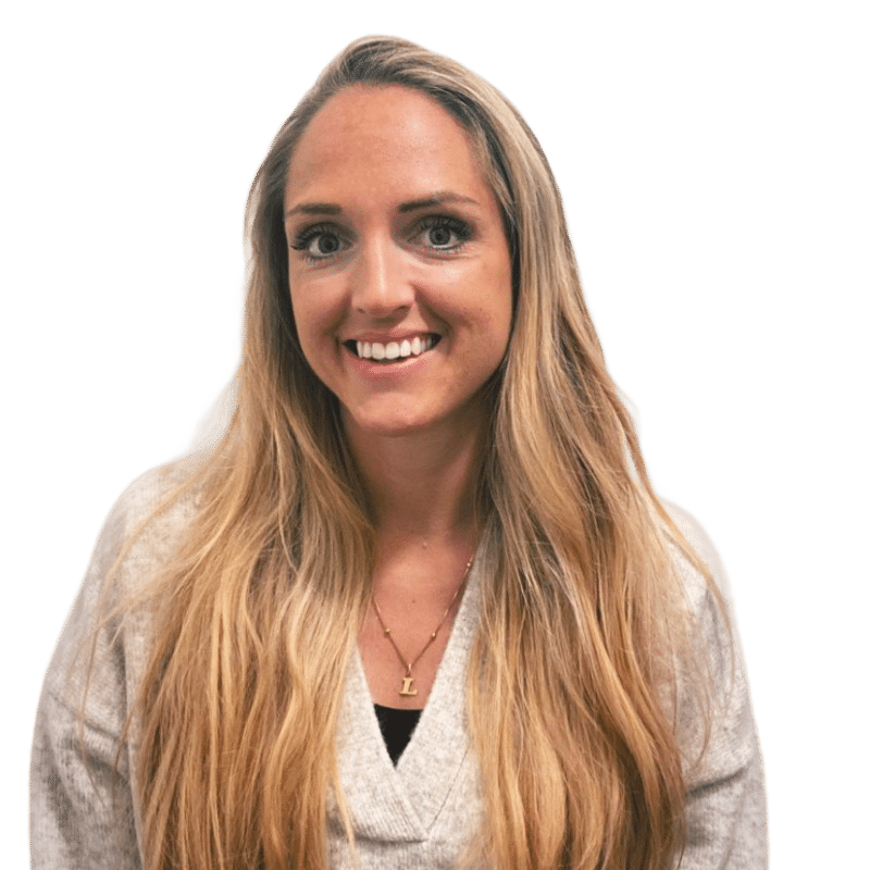 A woman with long blonde hair, wearing a light beige jumper and a necklace with a rectangular pendant, smiles against a plain white background.