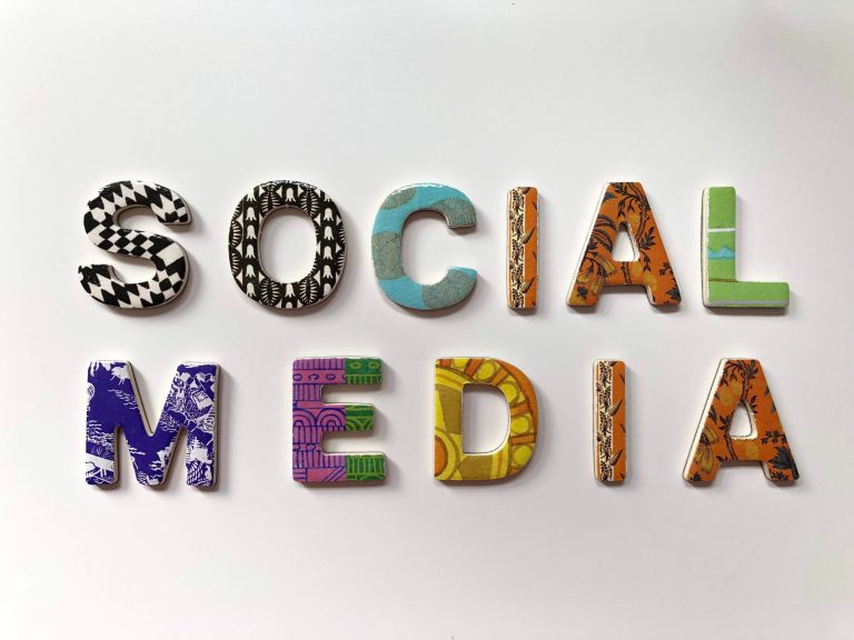 Des lettres colorées et ornées de motifs, formant l'expression « SOCIAL MEDIA », sont disposées sur un fond blanc. Chaque lettre présente un design unique, comprenant des formes géométriques, des vagues et des motifs abstraits.