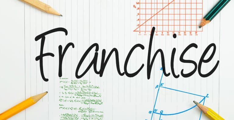 La palabra «Franchise» está escrita en letras grandes en un papel rayado, rodeada de lápices y de coloridos gráficos y fórmulas matemáticas.