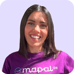 Mujer sonriente con el pelo liso y oscuro, que lleva una camiseta morada de Mapal OS, de pie sobre un fondo morado claro.