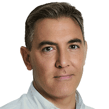 A man with short, neatly combed brown hair, light skin, and brown eyes is wearing a white collared shirt and looking at the camera with a neutral expression against a plain white background.