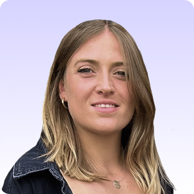 A woman with straight, shoulder-length blonde hair, wearing a black jacket and a gold necklace, stands in front of a light purple gradient background.